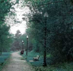 Teal park bench under soft Victorian streetlights, symbolizing reflection, grief, and quiet healing on the anniversary of 9/11.